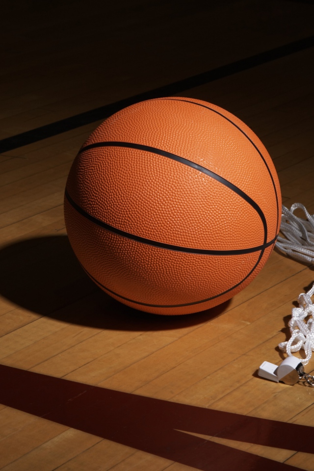 Баскетбольный мяч, свисток  и сетка на полу в спортзале 