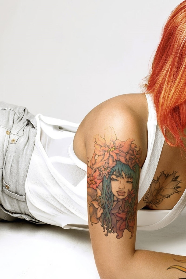 Красивая рыжеволосая девушка с пирсингом и татуировками