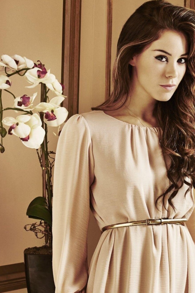 Брюнетка актриса Роксанна Макки стоит рядом с цветком орхидеи