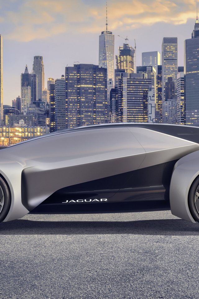 Серебристый электрический автомобиль  Jaguar Future-Type на фоне небоскребов