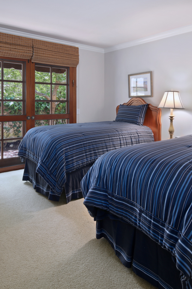 Две большие кровати в спальне с деревянным окном