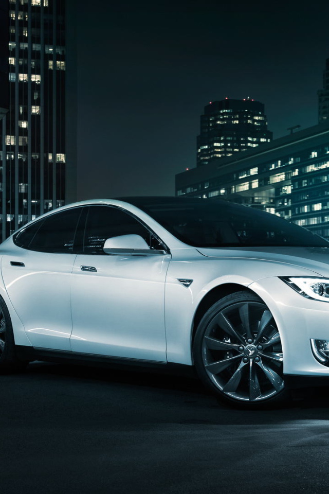 Белый электромобиль Тесла на фоне города 