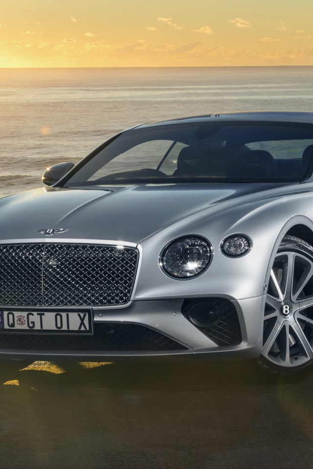Серебристый Bentley Continental GT 2018 года на фоне моря