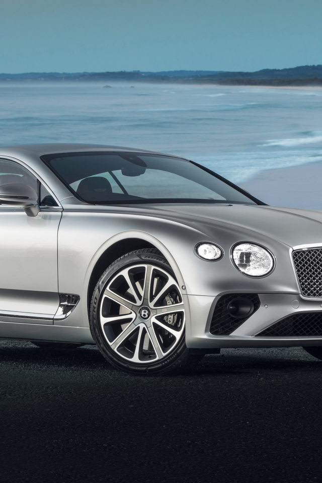 Серебристый автомобиль Bentley Continental GT 2018 года на фоне океана 