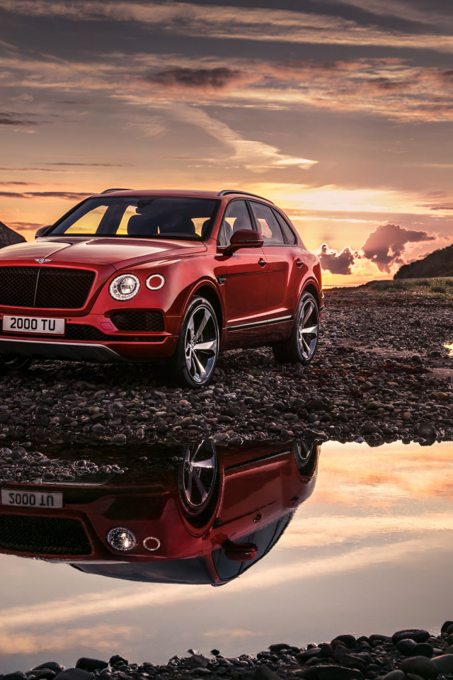 Красный автомобиль Bentley Bentayga V8, 2018 года на фоне заката 