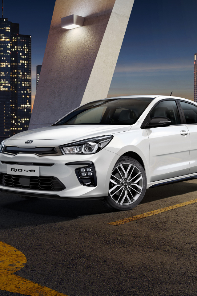 White car hatchback Kia Rio GT Line, 2018 on a background of a night city