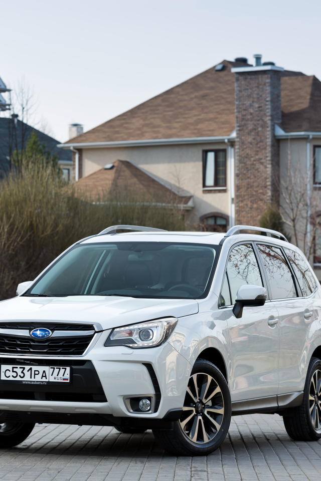 Белый автомобиль Subaru  Forester на улице у домов