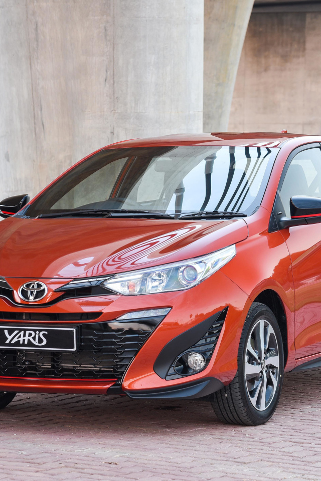 Красный автомобиль Toyota Yaris под мостом 