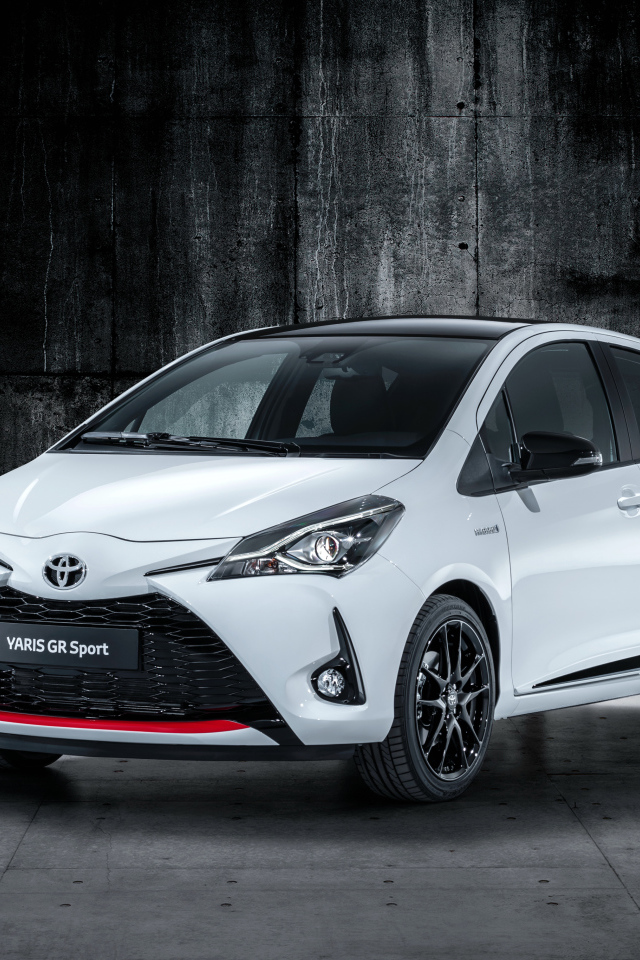 Белый автомобиль Toyota Yaris на сером фоне 