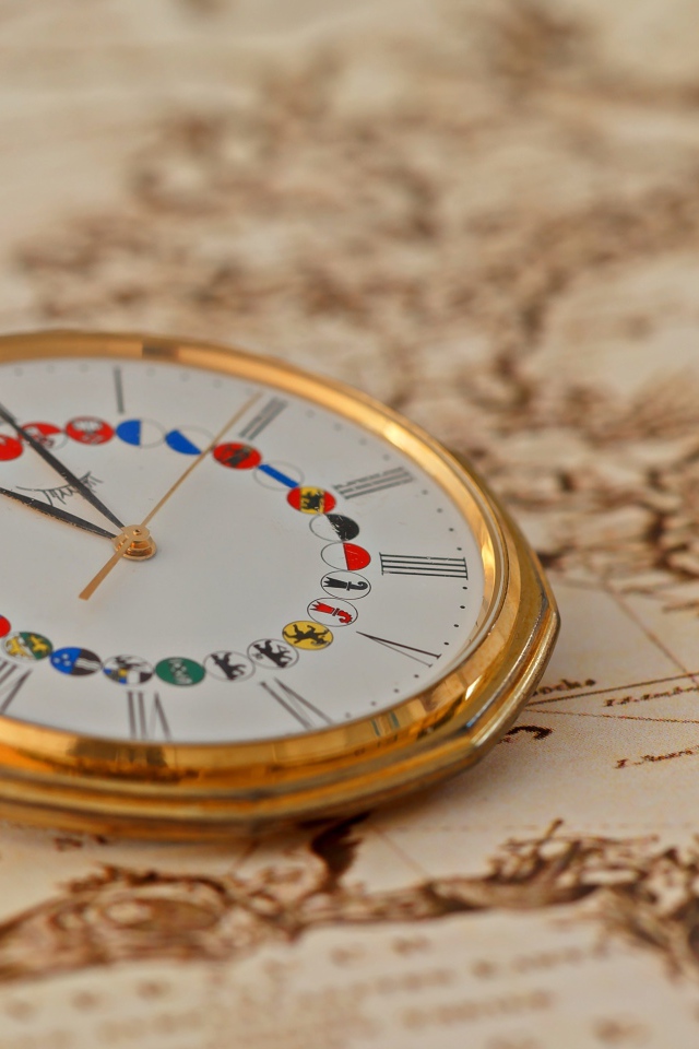 Карманные часы в золотой оправе лежат на карте
