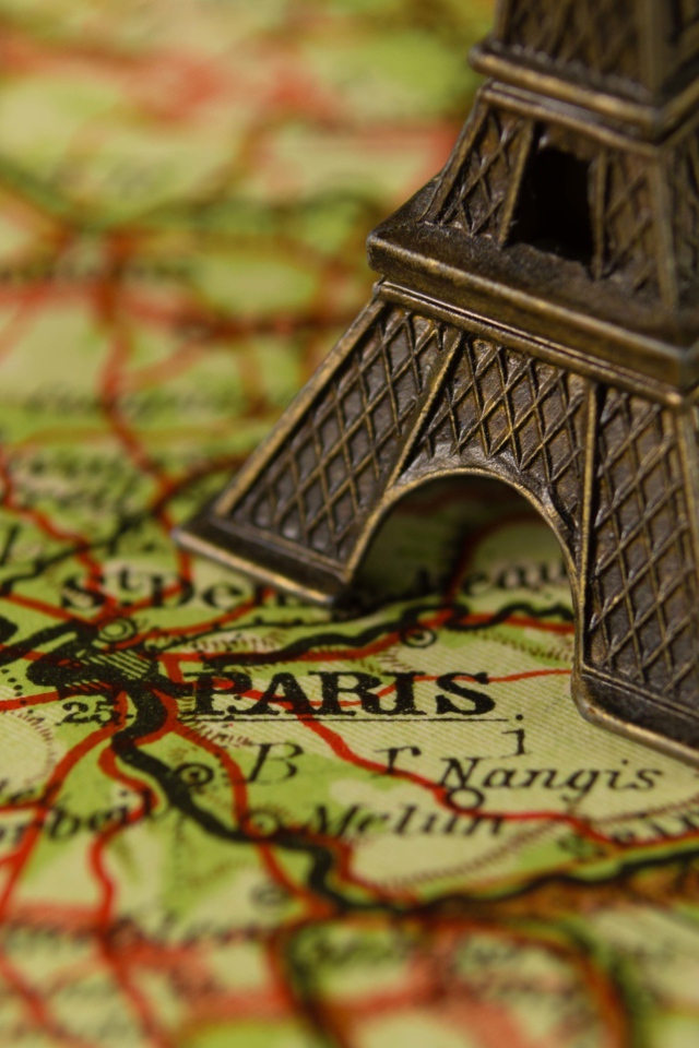 Маленькая статуэтка Эйфелева башня стоит на карте