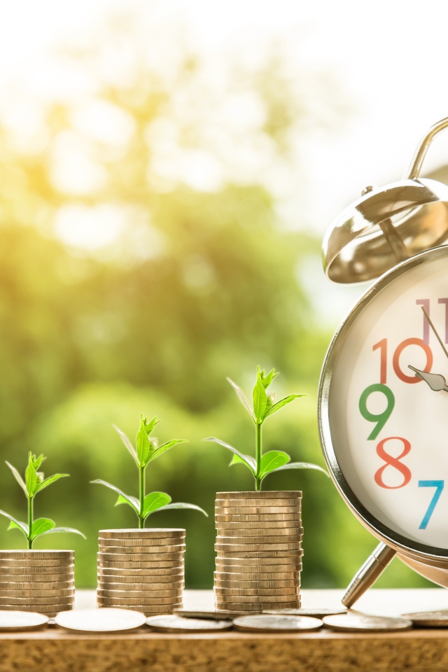 Будильник с монетами с зелеными ростками