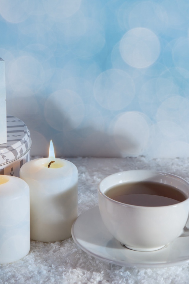 Свечи, чашка чая и фигура лошади на столе 