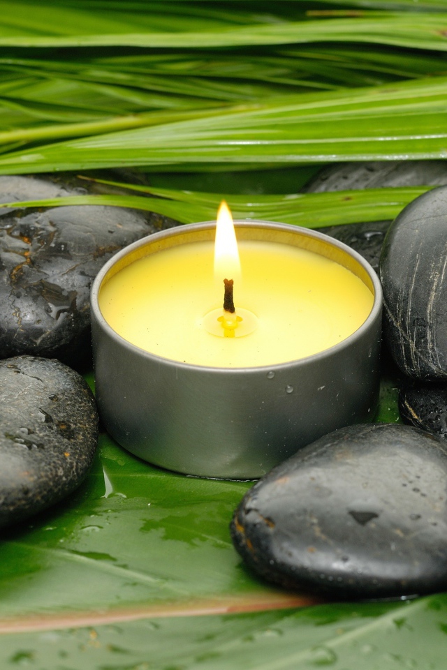 Зажженная свеча и черные камни для SPA