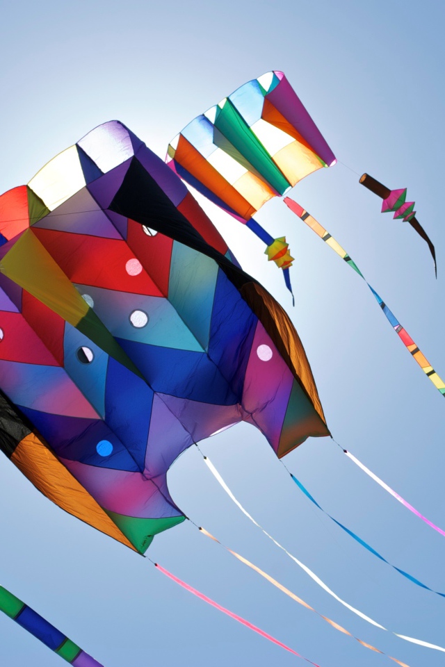 Разноцветный воздушный змей в голубом небе в лучах солнца