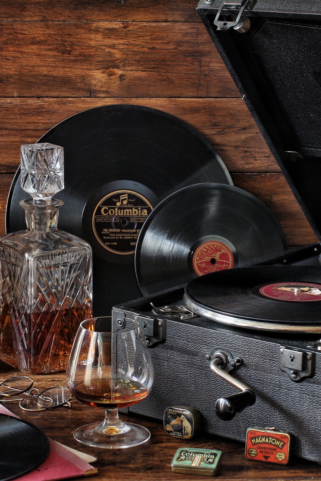 Старый граммофон с виниловыми пластинками, часами и коньяком на столе