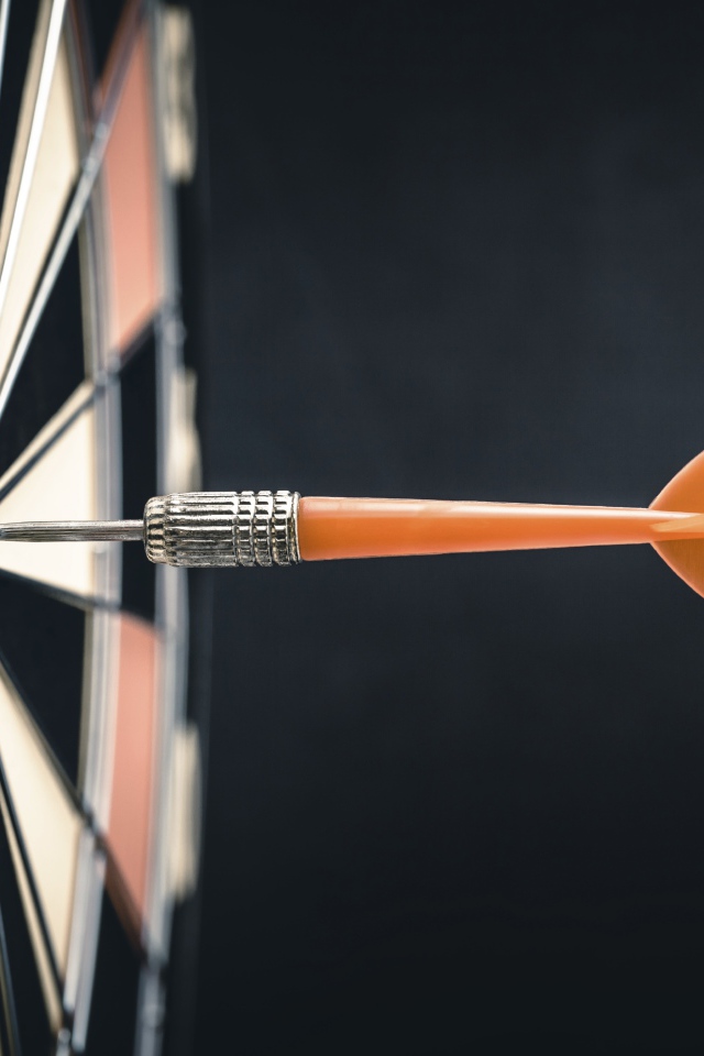 Оранжевый дротик в доске для дартса 