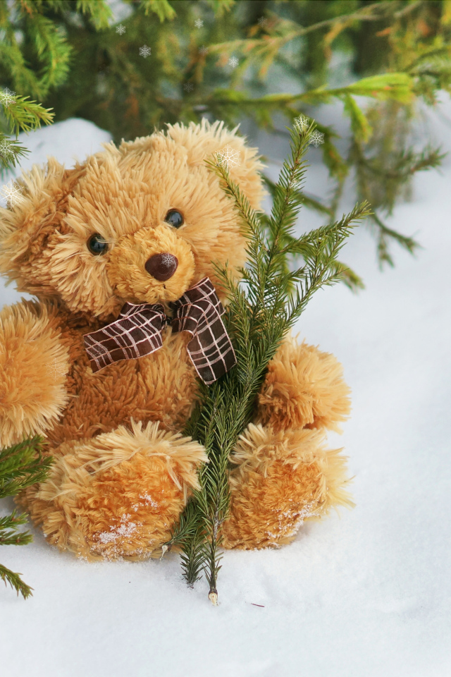 Плюшевый медвежонок на снегу с еловыми ветками