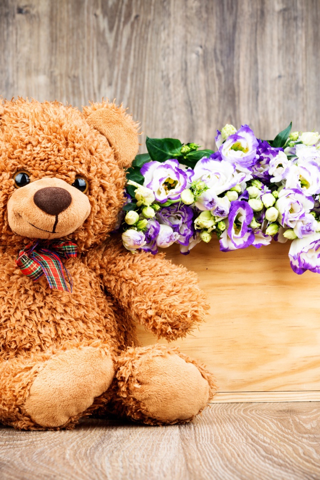 Плюшевый мишка с букетом цветов на деревянном фоне