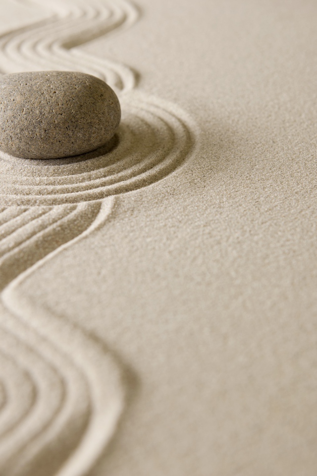 Камень лежит на рисунке на песке, дзен