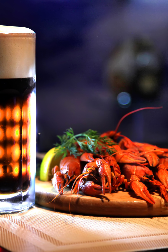 Бокал пива с вареными раками на столе
