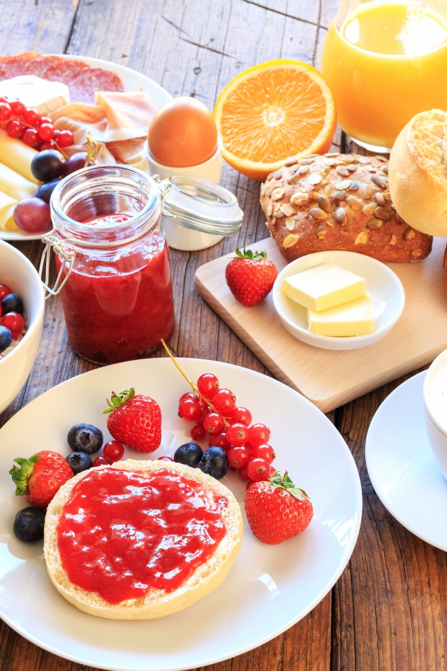 Аппетитный завтрак на столе с бутербродами, кофе и ягодами