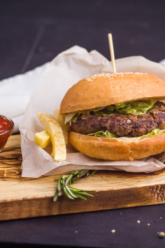 Аппетитный гамбургер с картофелем фри и кетчупом на столе