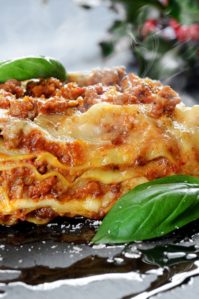 Аппетитная горячая лазанья с базиликом на столе