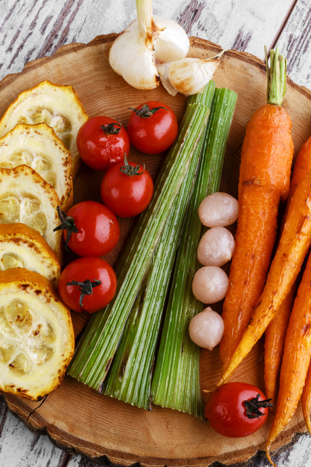 Печеные кабачки, помидоры, морковь, сельдерей и чеснок на разделочной доске