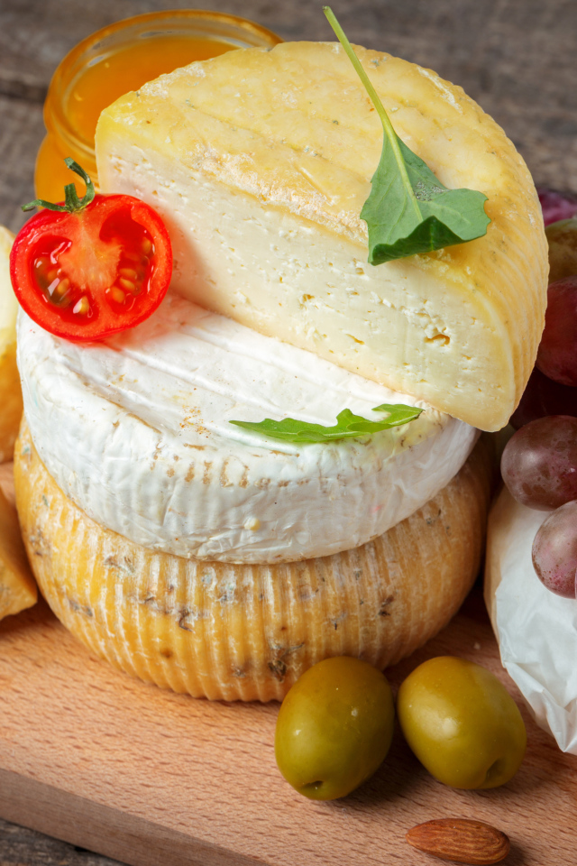 Сыр на разделочной доске с виноградом и оливками