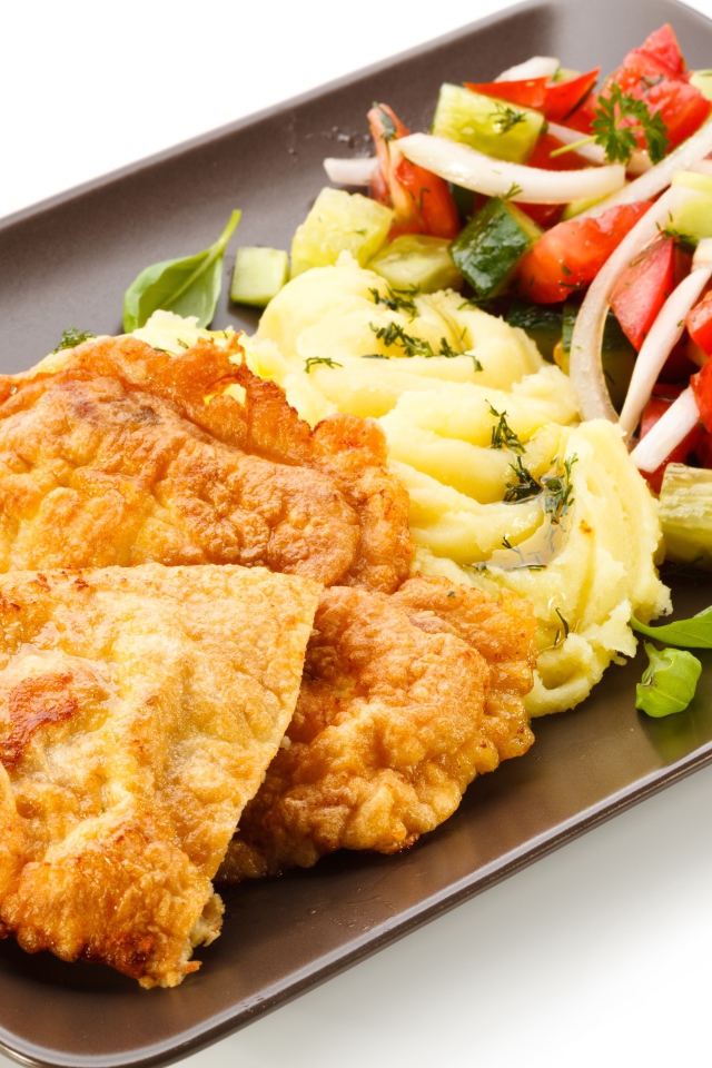 Отбивные с пюре и овощным салатом на тарелке