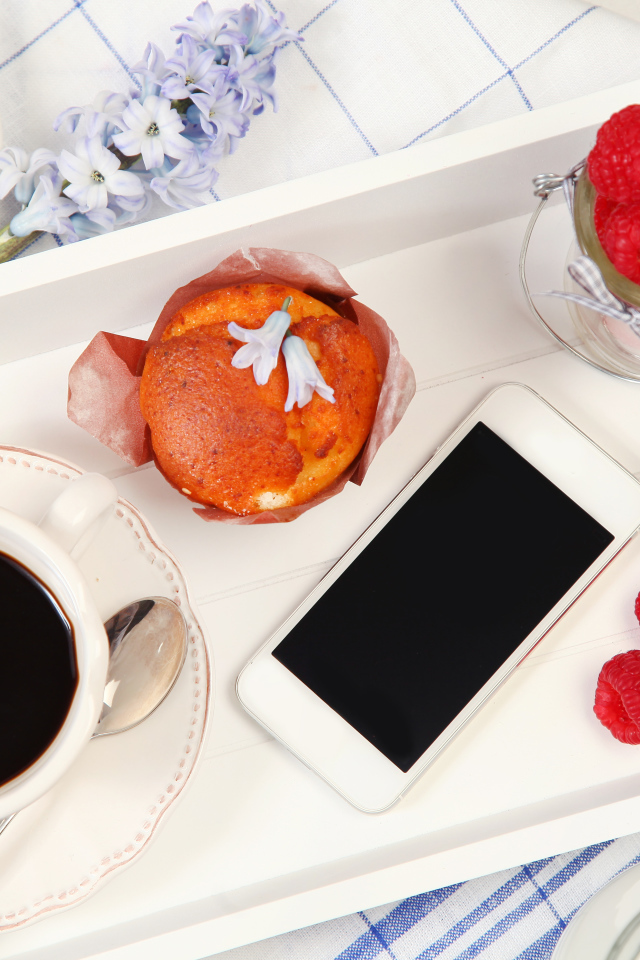 Кофе с кексом, хлопьями и малиной на столе со смартфоном 