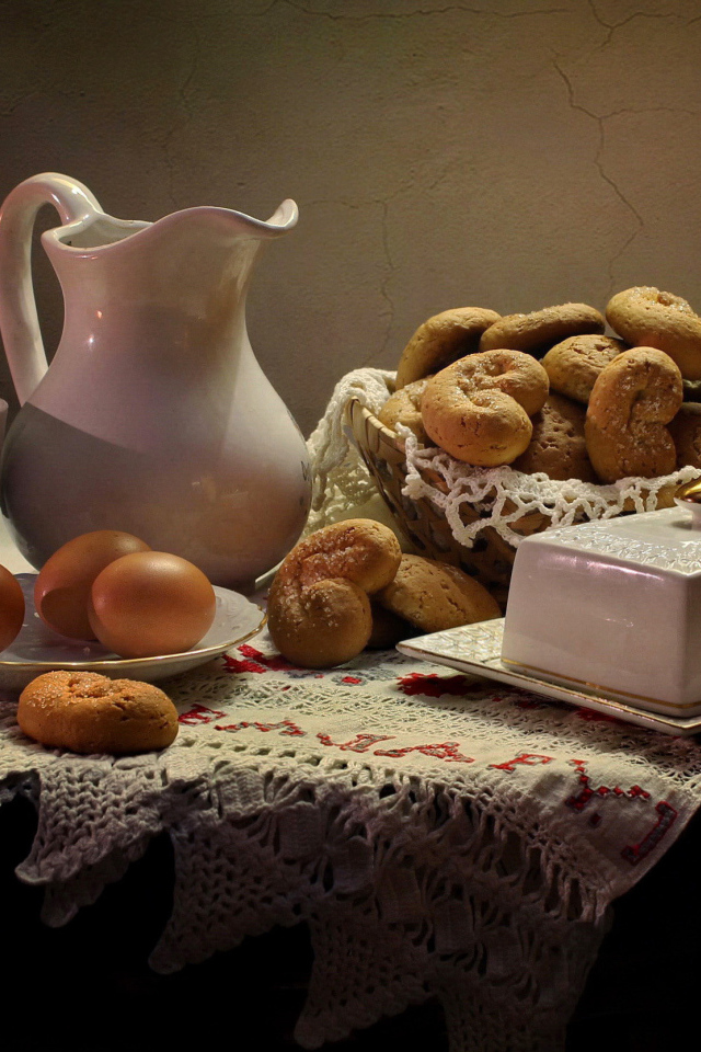 Вареные яйца на столе с кувшином, выпечкой и масленкой 