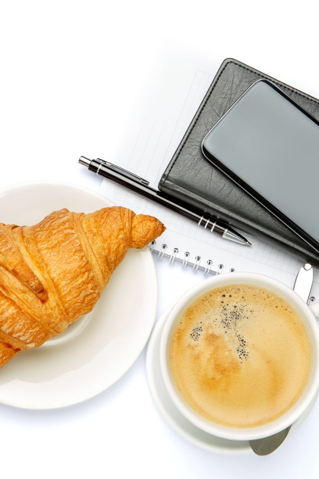 Чашка кофе, круассан, блонтон и смартфон на белом 