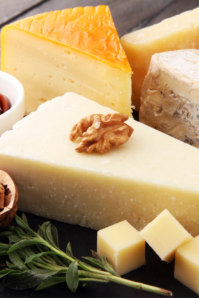 Разные виды сыра на столе с медом и грецкими орехами