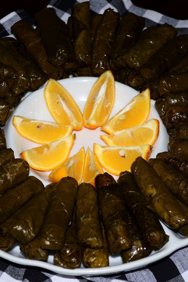 Долма на большом блюде с кусочками апельсина 