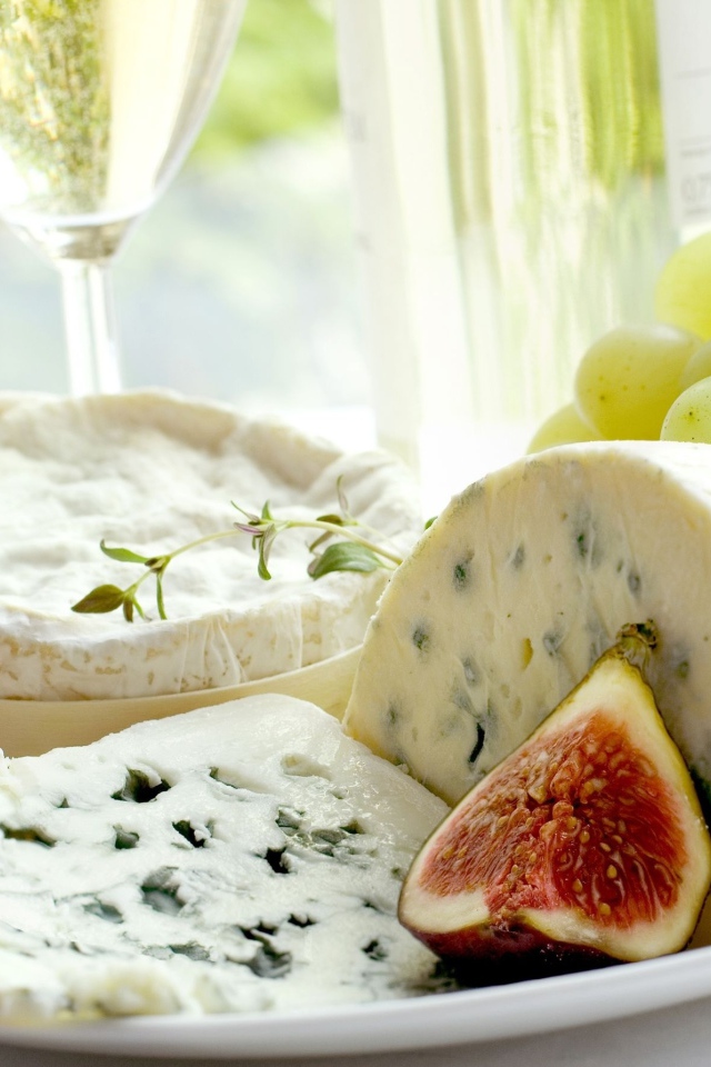 Дорогой сыр с плесенью на тарелке с инжиром и белым виноградом