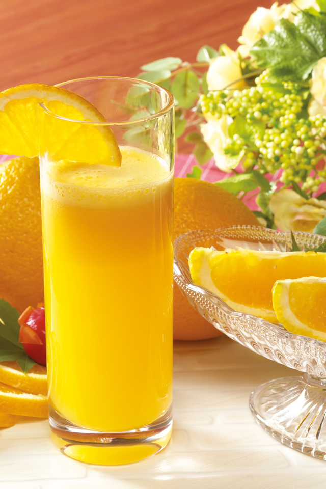 Свежий апельсиновый сок на столе с фруктами и цветами