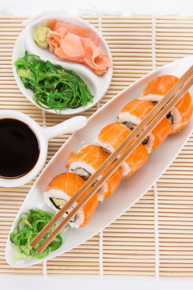 Японские суши на столе с соевым соусом и имбирем с салатом