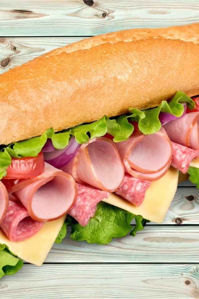 Большой бутерброд с колбасой, сыром и листьями салата