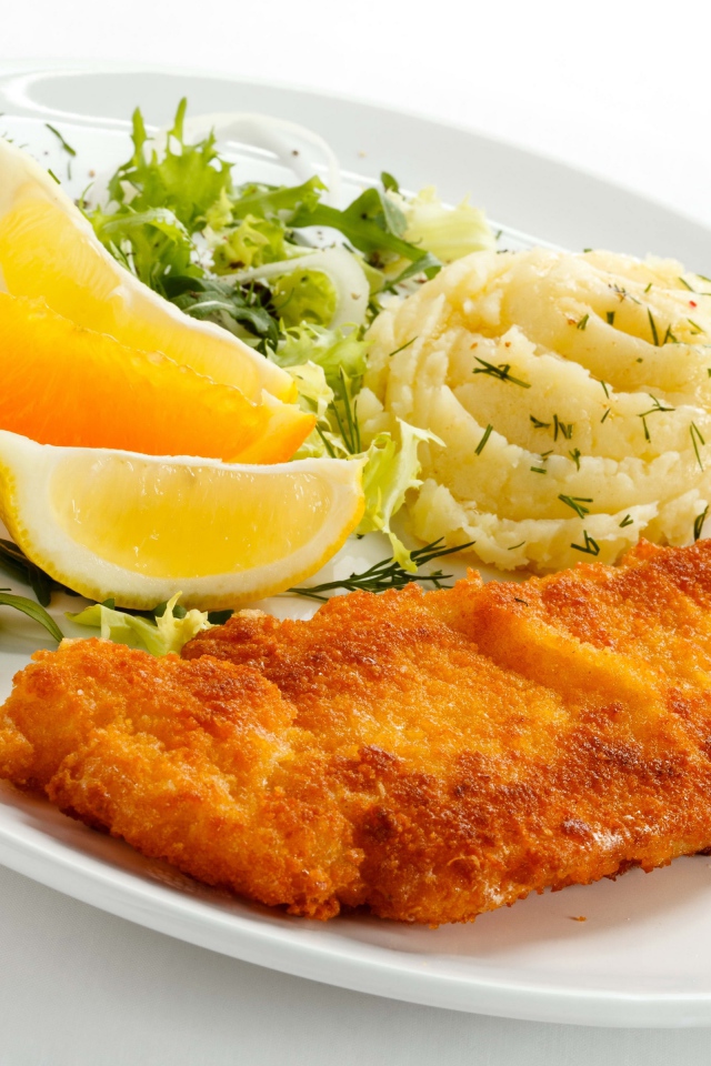 Картофельное пюре с мясом, кусочками апельсина и салатом на тарелке