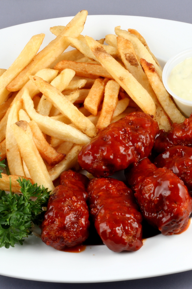 Тефтели в соусе с картофелем фри и петрушкой на тарелке