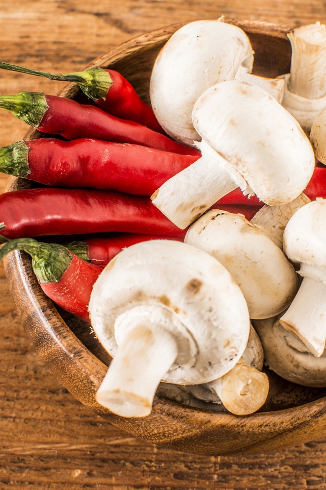 Грибы шампиньоны в деревянной миске с красным перцем