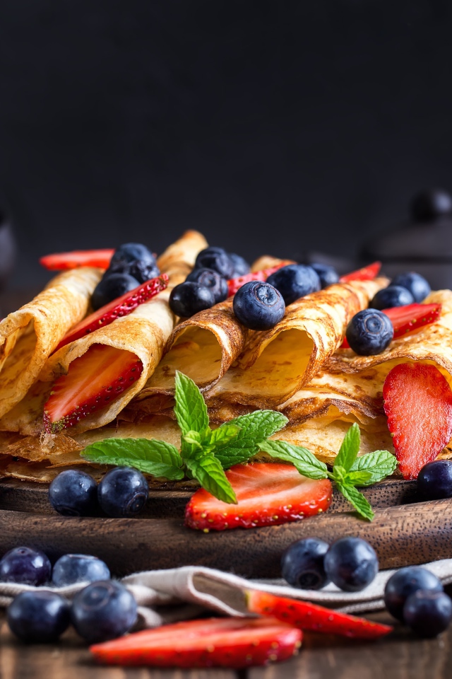 Блинчики с ягодами черники и клубники на столе