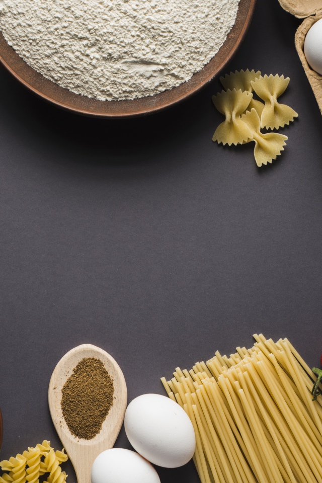 Паста, яйца, специи и помидоры на сером фоне