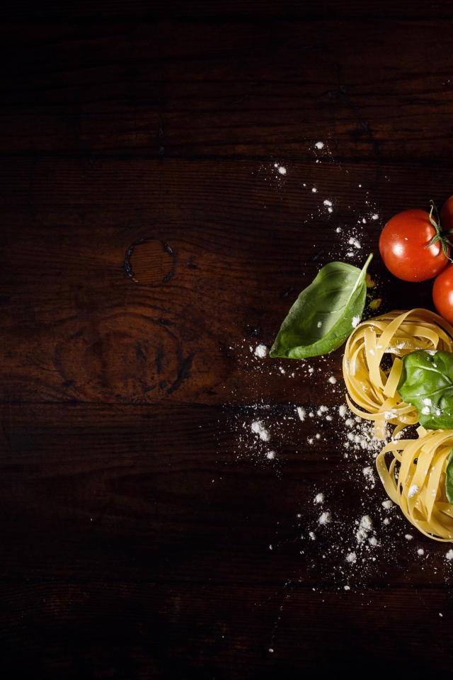 Паста с помидорами и листьями базилика на столе