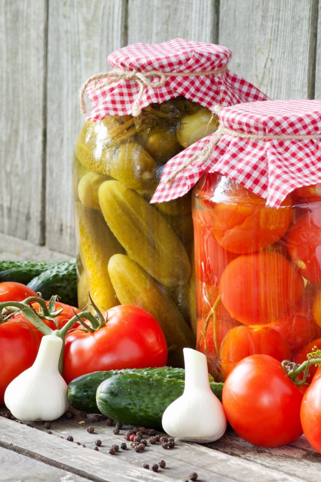 Соленья из огурцов и помидоров с овощами на столе