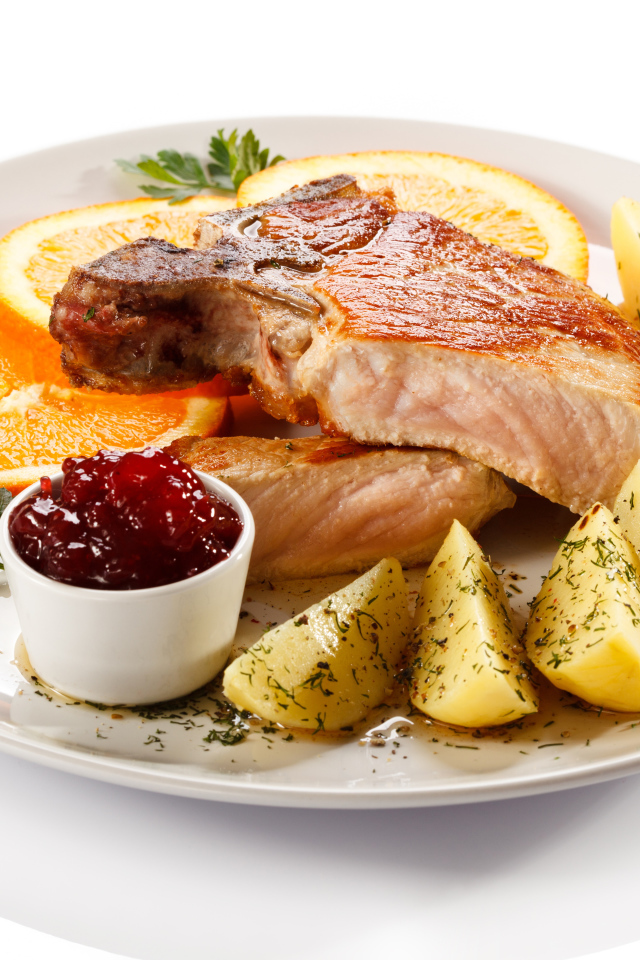 Картофель с мясом и кусочками апельсина на тарелке