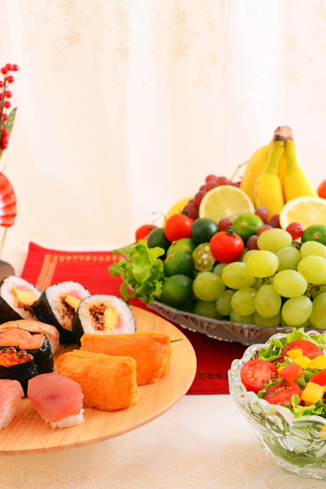 Роллы на столе с овощным салатом и фруктами 