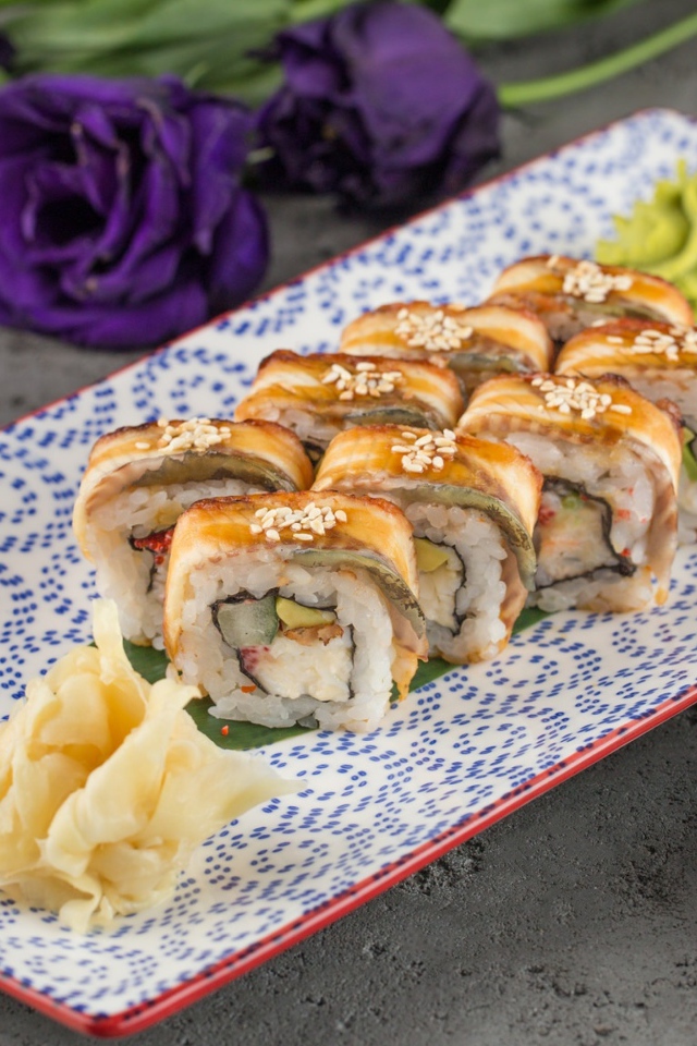 Роллы с авокадо и соевым соусом на столе с цветами 